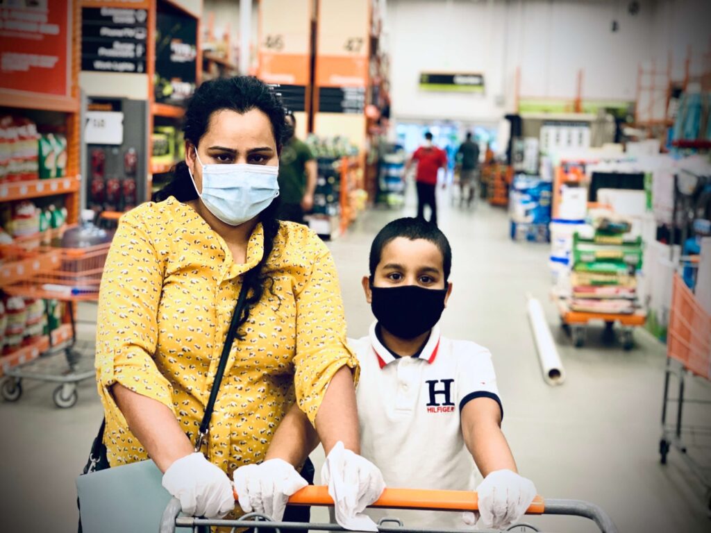 Mother and child pushing a cart through a grocery store while wearing protective masks