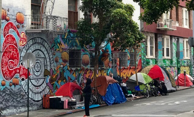 Tents alongside a mural in San Francisco