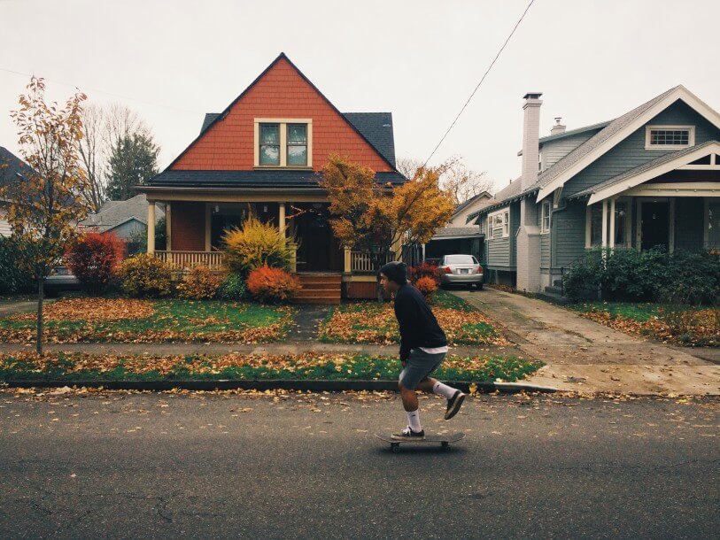 A young man skateboards past an old house in Portland, Oregon