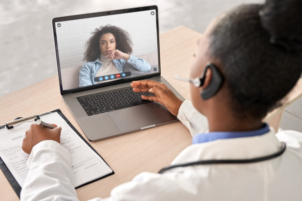 Black doctor meets with patient virtually for telehealth appointment