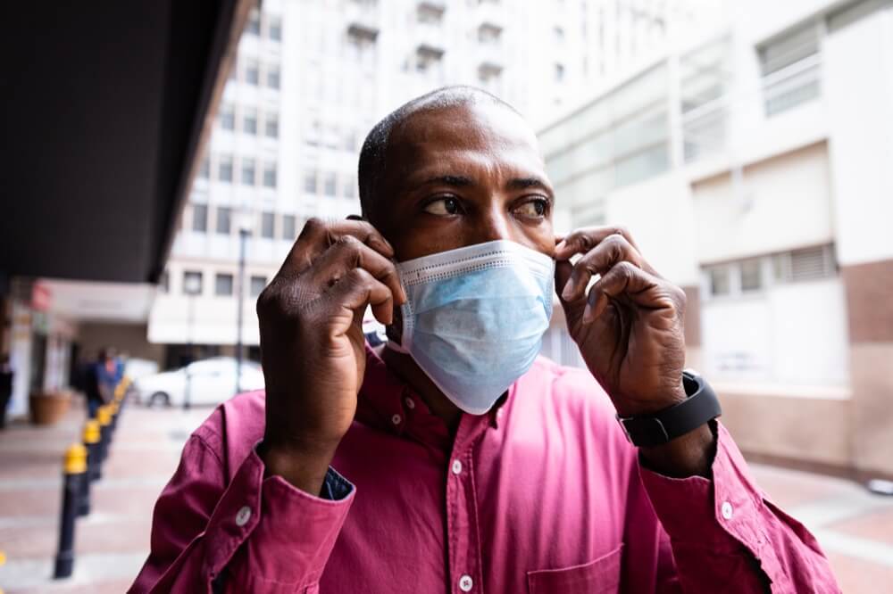 Black man puts on surgical mask