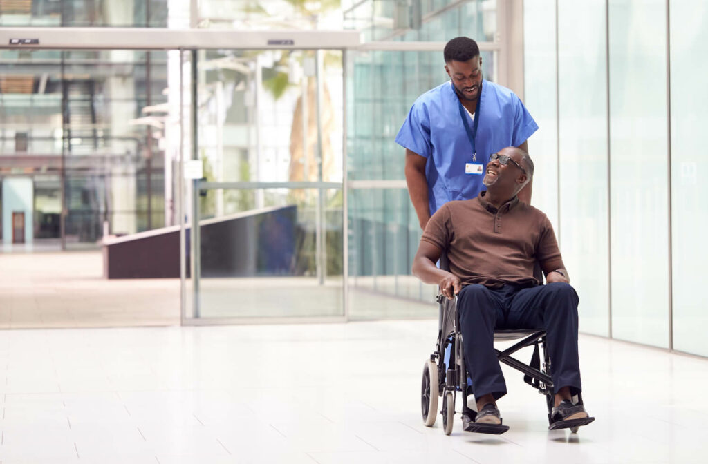 Black healthcare professional wheels patient in wheelchair