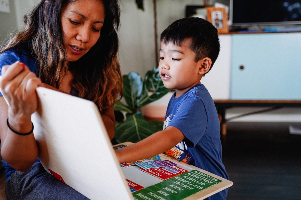 Asian toddler playing on laptop with mother