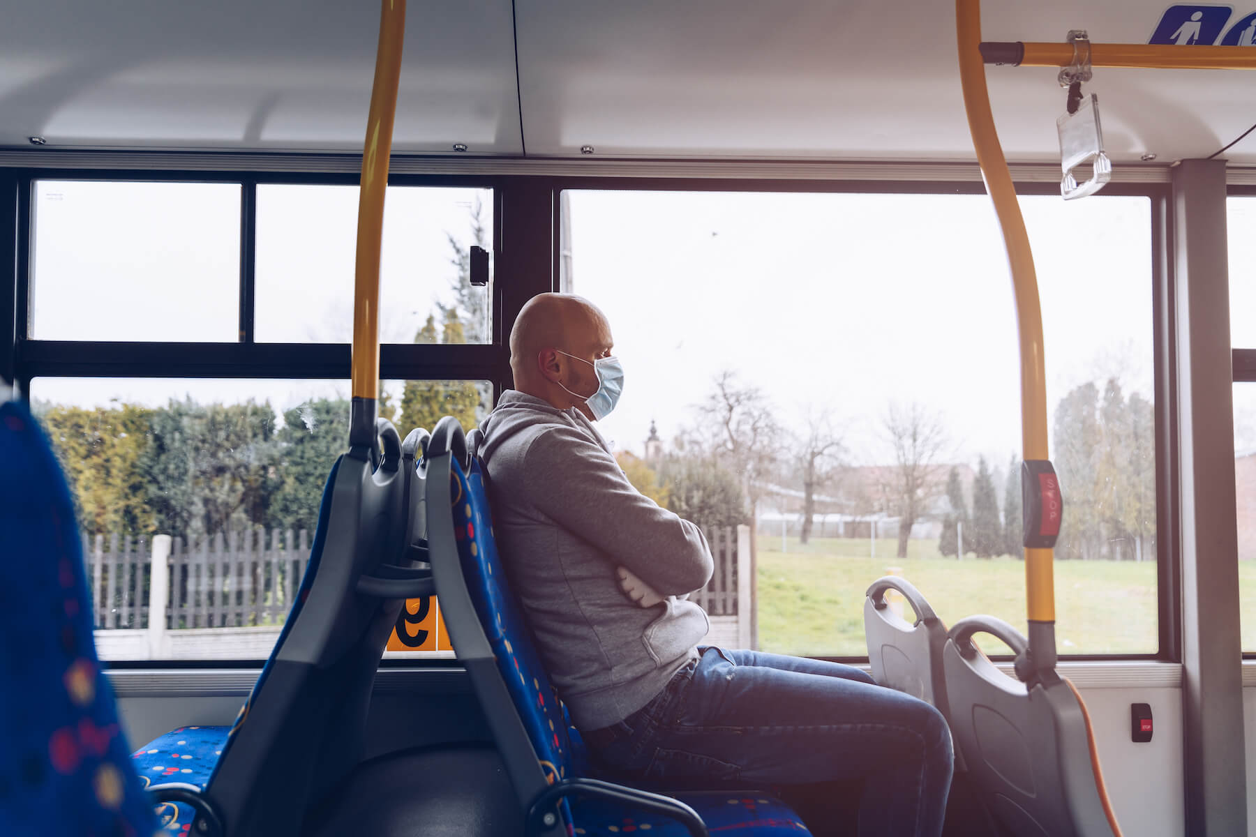 Man wearing protective mask sits on bus during the day