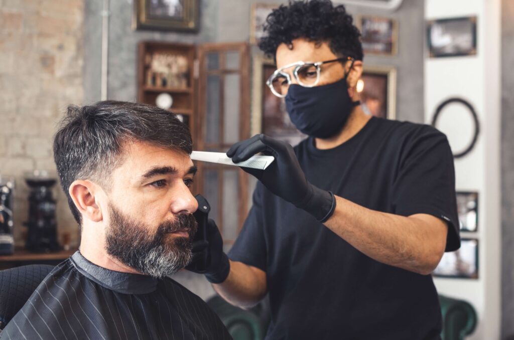 Masked hairdresser combing a client's hair