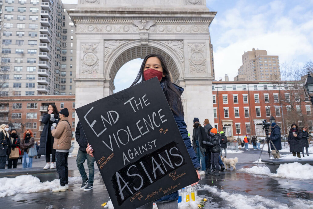 Demonstrator at a rally holds sign that reads, "end the violence against asians"