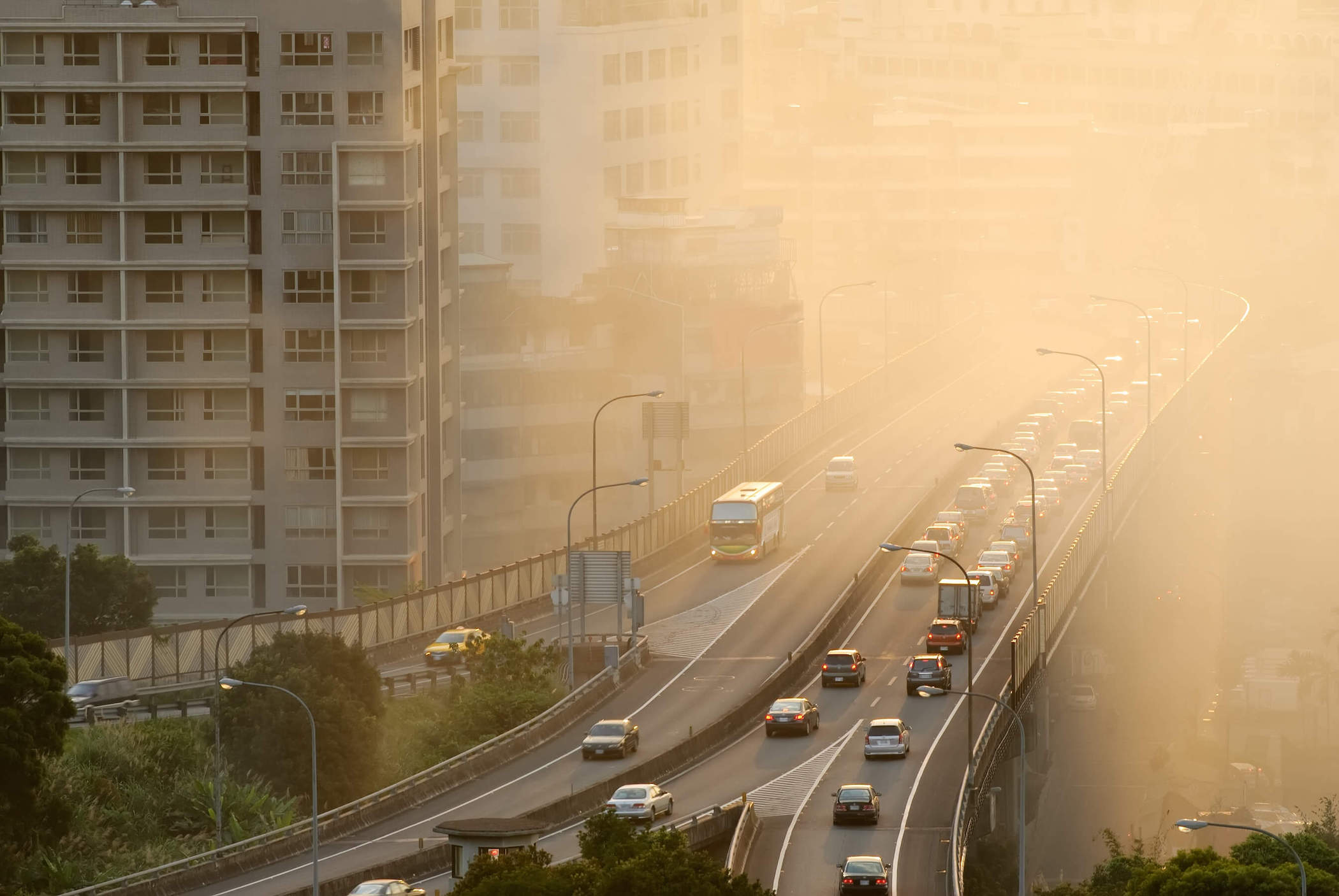 Air pollution scenic with cars on highway and yellow smoke in city.