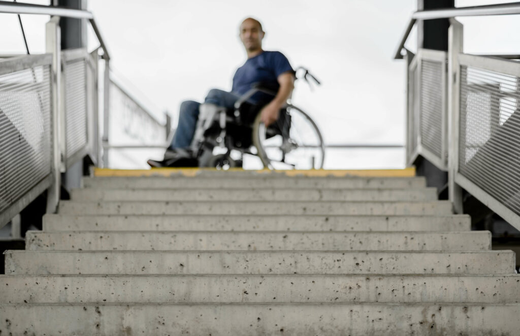 Wheelchair user at top of stairs subway entrance