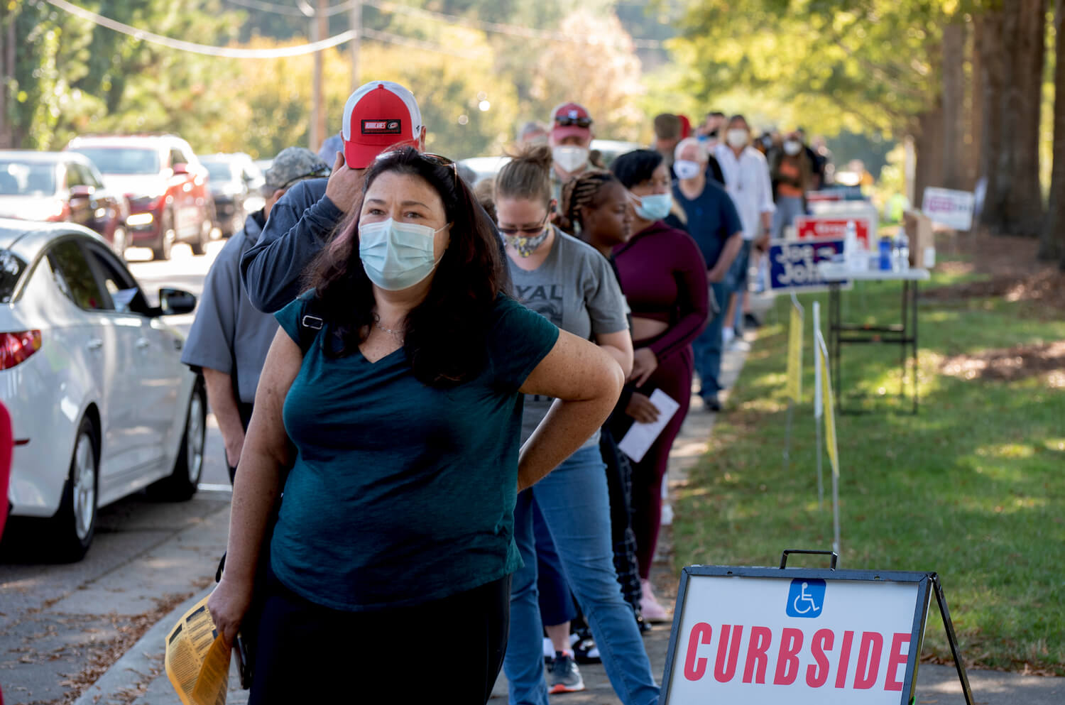 A lady wearing a face mask is amongst a diverse group of voters on the first day of early voting.