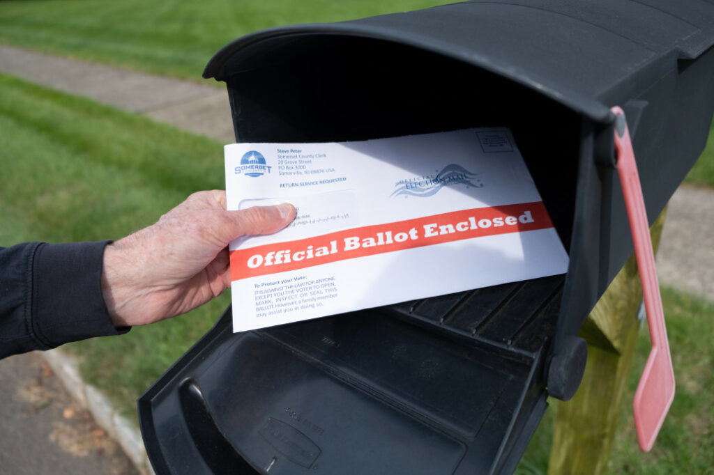 person placing a mail-in ballot into a mailbox