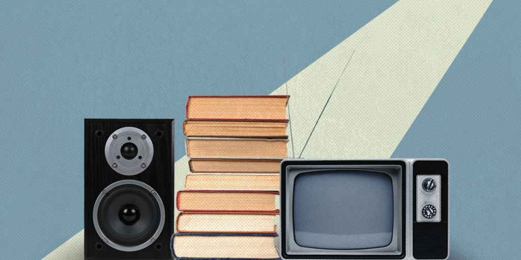 A spotlight shines on a stereo, stack of books, and old school television