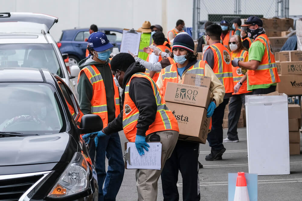 Volunteers load food into the trunk of vehicles during a ''Let's Feed L.A. County'' drive thru food distribution by the Los Angeles Regional Food Bank, April 23, 2021, in Rosemead, California. Ringo Chiu / Shutterstock.com